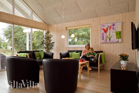 Allrummet är inrättat med komfortabel soffgrupp, kakelugn och tv