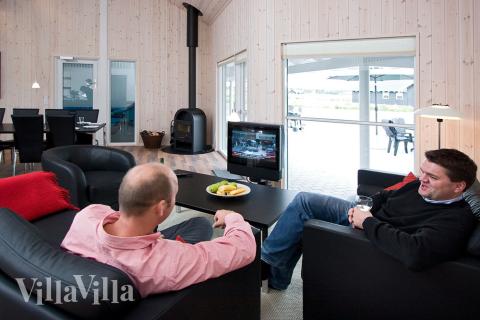 Komfortabla möbler, plattskärms-tv och kakelugn skapar en mysig och avslappnad miljö i huset